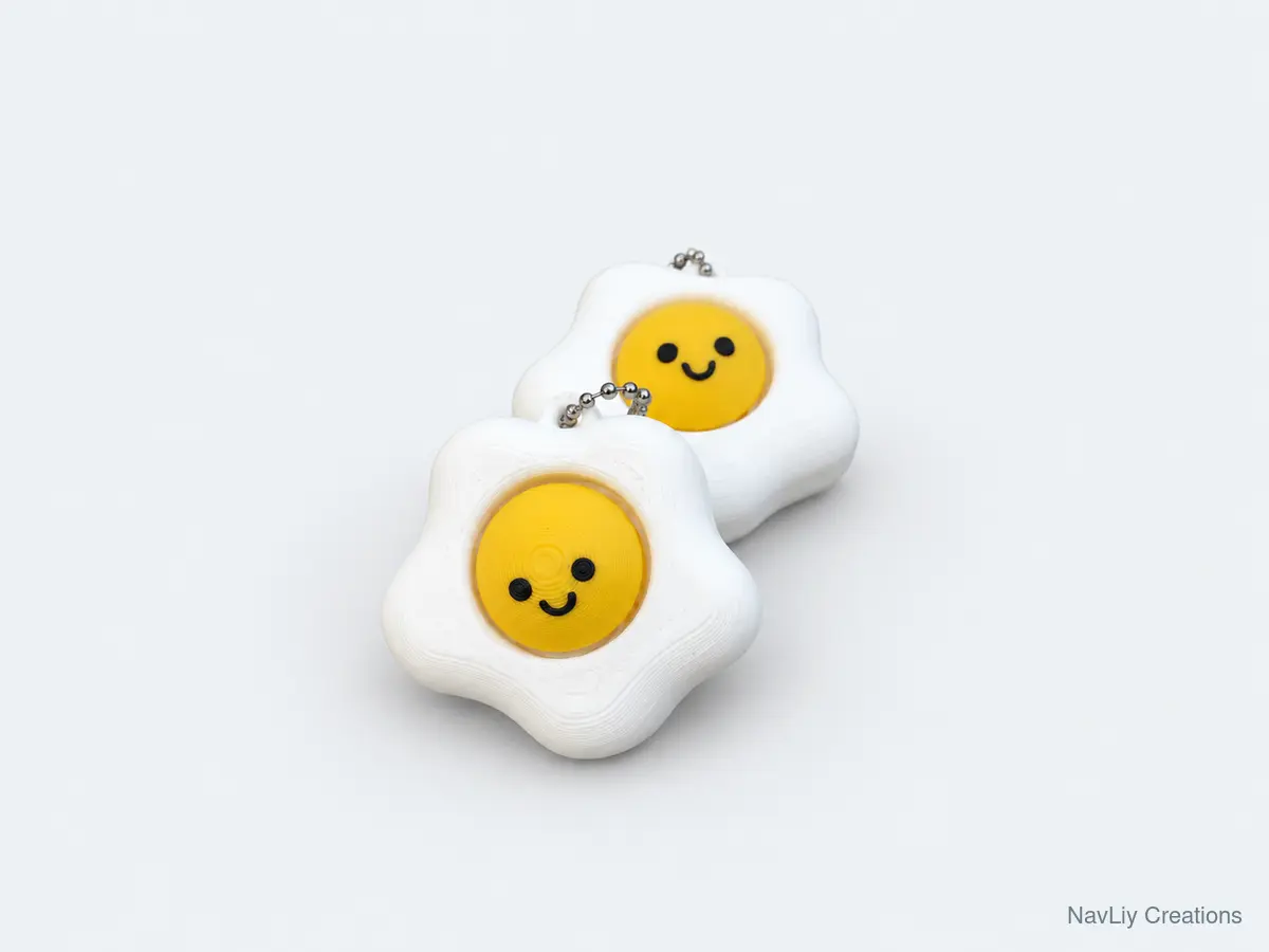 Pair of white fried-egg keychains with yellow smiling centers